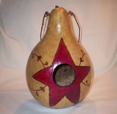 a pear shaped vase with a red star painted on the side and a hole in the middle