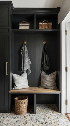 a bench with two coats hanging on it and some baskets in front of the bench