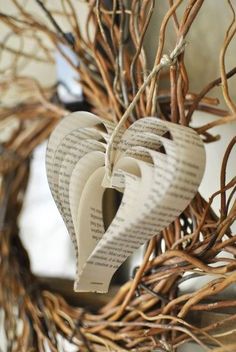 an ornament made out of book pages is hanging from a twig wreath