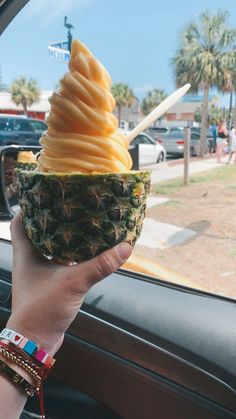 a person holding an ice cream sundae in their hand while driving down the street