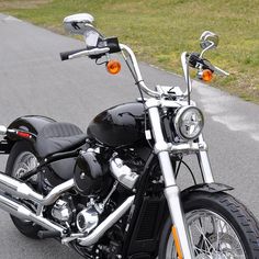 a black motorcycle parked on the street next to grass