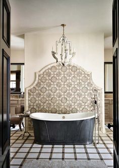 an ornate bathtub and chandelier in a bathroom with black and white tile