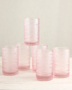 four pink glass tumblers sitting on top of a table