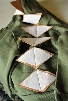 the back of a green jacket with white and brown stitching on it's sides