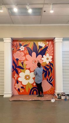 a person painting a mural on the side of a wall in an office building with shutters