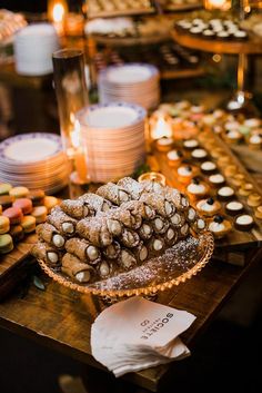 an assortment of pastries and desserts on a table with candles in the background