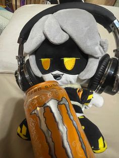 a stuffed animal wearing headphones and holding a can