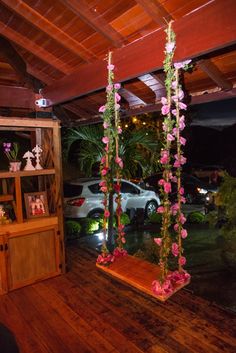 a room with wooden floors and pink flowers hanging from it's ceiling in front of a car