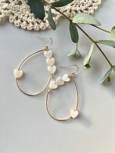 "Hearts-On-A-Wire earrings. The perfect addition to your Valentines Day outfit or any other day of the year!  Delicate shell, heart beads hand-wired on an 18k GF gold teardrop, wire hoop.  Part of our Minimal Lovey Line The Details: + 2.00\" long + Teardrop style + 18k Gold Filled + Shell heart beads  + Nickle Free + Lead Free" White Dangle Earrings For Valentine's Day, White Teardrop Jewelry For Valentine's Day, White Drop Earrings With Heart Charm, White Heart Drop Earrings For Pierced Ears, White Hoop Earrings With Heart Charm For Gift, White Dangle Hoop Earrings For Anniversary, White Drop Earrings With Heart Beads, White Dangle Hoop Earrings For Valentine's Day, White Heart Drop Earrings