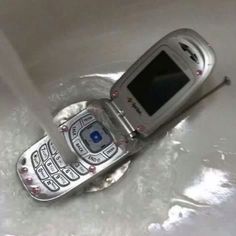 an old cell phone sitting in a sink with water coming out of it's side