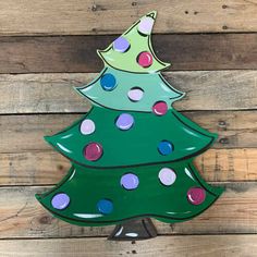 a green christmas tree with polka dots on it sitting on top of a wooden wall