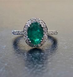 DeKara Designs Collection Our latest design! An elegant and lustrous Colombian Emerald surrounded by beautiful diamonds in a halo setting. Metal- 14K White Gold, .583. Stones- 1 Oval Colombian Emerald 1.25-1.40 Carats, 40 Round Diamonds, F-G color VS clarity, 0.30 carats. Latest of my creations. A beautiful Oval Colombian Emerald Halo Diamond Ring. The Emerald is a beautiful green and it is professionally prong set in between four double prongs. There are ten pave set round diamonds on each side Exquisite Oval Emerald Ring In Platinum, Luxury Diamond White Emerald Ring, Oval Shape, Luxury Oval Emerald Ring In Diamond White, Elegant Oval Emerald Diamond Ring, Diamond White Oval Emerald Ring, Dazzling Oval Emerald Ring In Platinum, Dazzling Round Emerald Ring With Halo Design, Oval Emerald Ring In Diamond White, Dazzling Oval Emerald Ring With Brilliant Cut