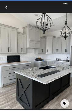 an image of a kitchen with white cabinets and granite counter tops in the center island