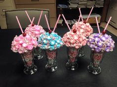 four vases filled with candy and candies on top of a black table next to a chair