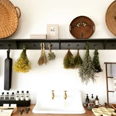 the kitchen counter is covered with spices and herbs hanging from hooks on it's wall