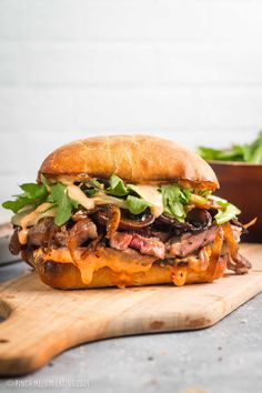 a sandwich with meat, cheese and lettuce on a cutting board