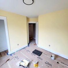 an empty room with yellow walls and white trim on the floor, including paint rollers