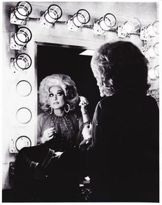 an old black and white photo of a woman brushing her hair in front of a mirror