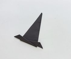 a black origami airplane on a white surface with one wing folded up to the side