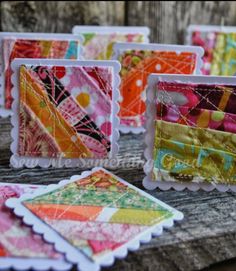 small cards with colorful designs on them sitting on top of a piece of wooden plank