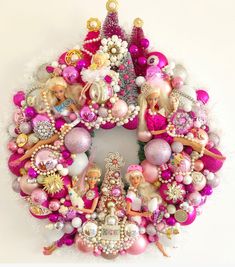 a christmas wreath with barbie dolls and other ornaments on the front, hanging from a white wall