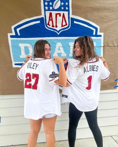 two women in baseball uniforms standing next to each other