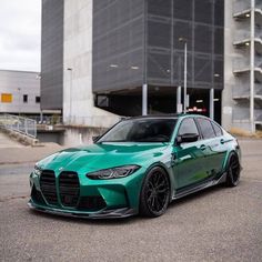 a green car parked in front of a building with large windows and black rims