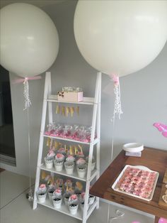 two white balloons and some cupcakes on a table