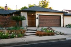 a house with landscaping in front of it and two garage doors on the side of the house