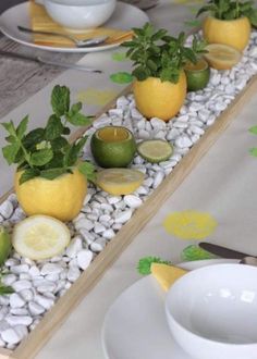 the table is set with lemons, limes and other fruit on rocks in an arrangement