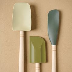 two spatulas, one green and the other white are on a beige surface