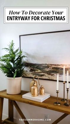 a table with candles, potted plants and a painting on the wall above it that says how to decorate your entryway for christmas