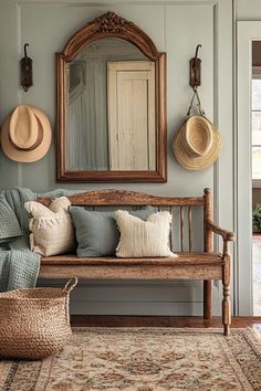 a wooden bench sitting under a mirror next to a basket filled with pillows and hats