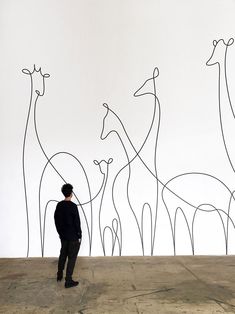 a man standing in front of a wall with giraffes drawn on it