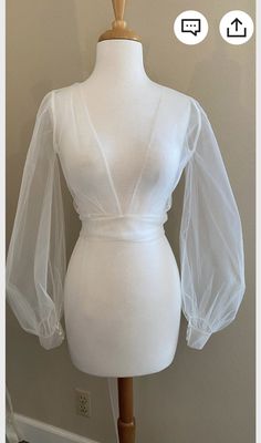 a mannequin wearing a white top with sheer sleeves on it's shoulders