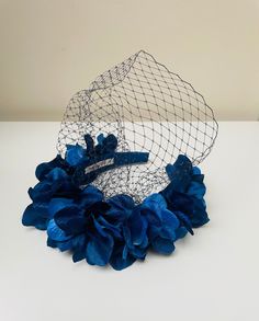 FABRIC This Women's fascinator headband has been carefully hand made. The head crown has been covered with a crepe blue silk fabric with royal blue hydrangea flowers attached securely within the headband fabric. This piece is poles apart from the others on the market which have the flowers glued to a cheap synthetic chunky halo bands The flower crown light, soft and super comfortable to wear and boasts a quality finish.  FIT  A flexible base band to fit all head sizes.  PACKAGING Each headband i Evening Headpiece With Handmade Flowers And Pinched Crown, Summer Blue Headpiece With Handmade Flowers, Blue Crown Headpiece For Party, Blue Party Crown Headpiece, Blue Handmade Flowers Fascinator For Races, Floral Decorated Headband For Party, Flower Decorated Headband For Party, Evening Headpiece With Handmade Flowers And Structured Crown, Evening Headpiece With Handmade Flowers