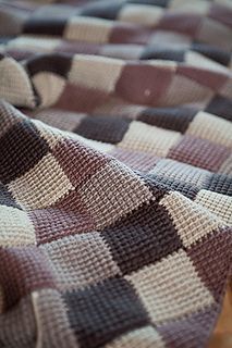 a close up of a checkered blanket on a wooden table with a blurry background