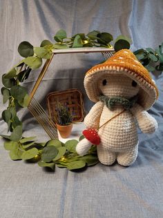 a crocheted teddy bear wearing a straw hat and holding a heart