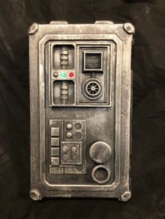 a metal object is sitting on a black surface with buttons and other items around it