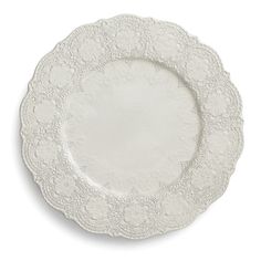 an empty white plate with lacy designs on the rim and bottom, set against a white background