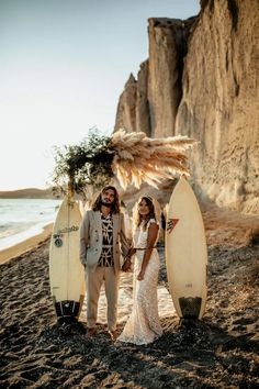 a man and woman standing next to surfboards on the beach