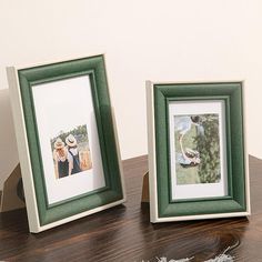 two framed pictures sitting on top of a wooden table