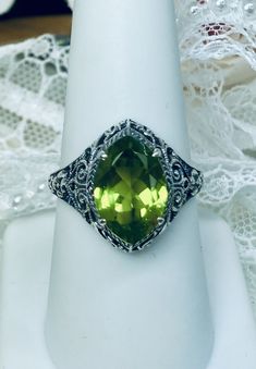 Natural Green Peridot Ring Iris Design#201 Custom Made This is a stunning Art Deco vintage reproduction ring in sterling silver filigree with a 3.12 carat Natural green peridot gemstone. The brilliant natural gem is 13mm in long by 9mm wide. The ring is 17mm North-South on the finger. The inside of the band is marked 925 for solid sterling silver. This is a lovely reproduction of a vintage antique filigree ring. There is beautiful craftsmanship evidenced in the silver filigree setting. See the f Classic Green Gemstones With Accents, Classic Green Gemstone With Center Stone, Art Deco Green Jewelry With Round Cut, Art Deco Green Round Cut Jewelry, Classic Peridot Jewelry With Accent Stones, Green Gemstone Accents Jewelry With Round Cut, Classic Green Marquise Rings, Art Deco Green Jewelry With Accent Stones, Green Art Deco Jewelry With Accent Stones