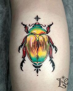 a colorful beetle tattoo on the right side of the leg, with black lines and cross