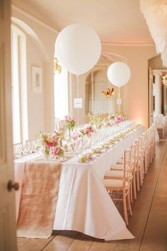 a long table is set with white and pink flowers, plates and glasses for an event