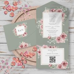 wedding stationery with pink flowers and greenery on the table next to a wooden platter