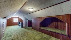 an empty room with wooden walls and green carpeted flooring in the middle of it