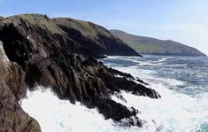 a man standing on top of a cliff next to the ocean