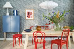 a dining room table with red chairs and blue cabinets