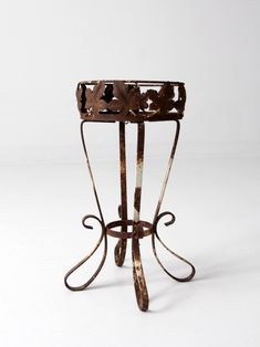 an old metal stand with flowers on it's sides and one section missing from the top